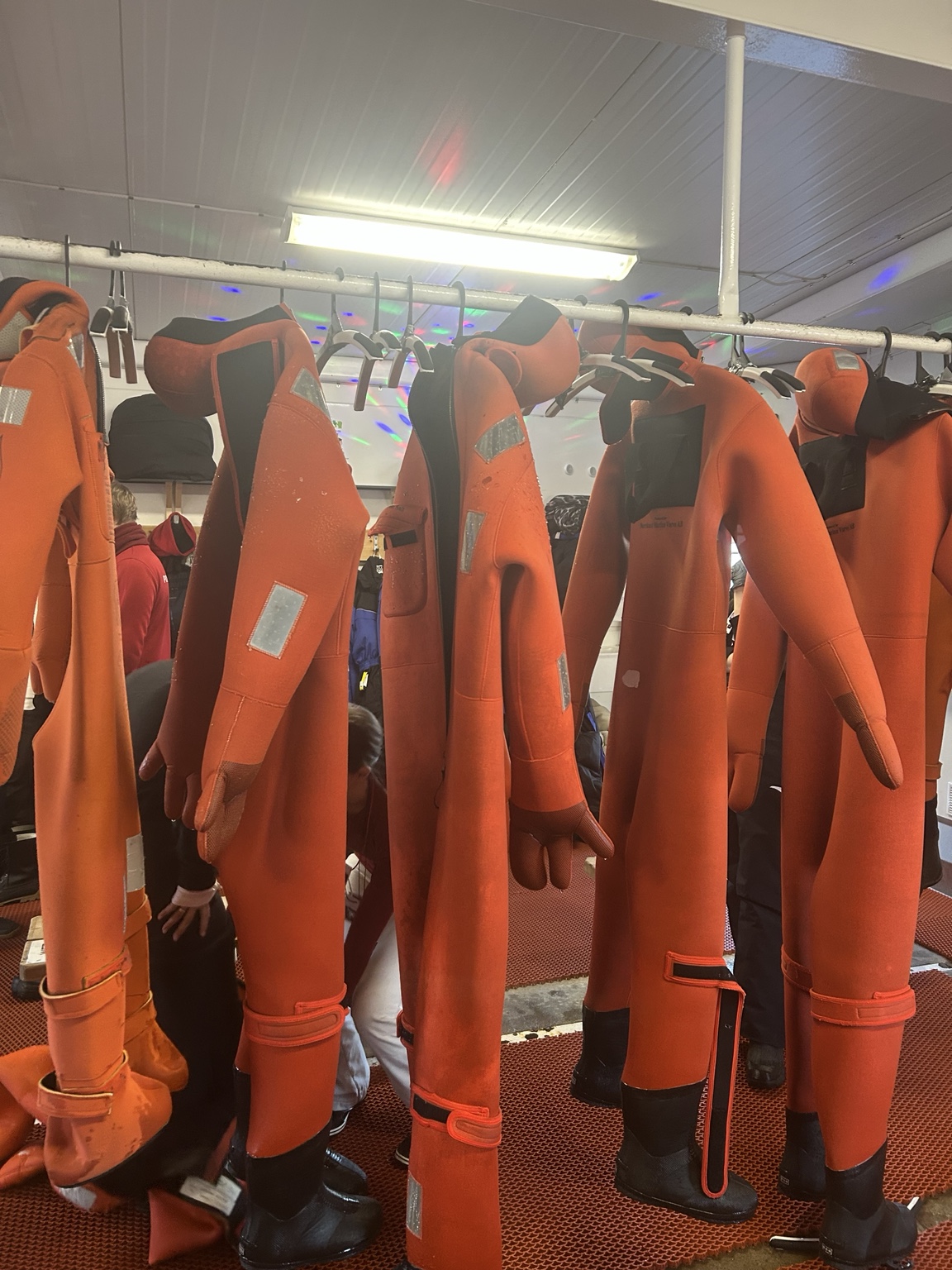 חליפות ציפה כתומות לקראת ציפה במים הקפואים במהלך שיט שוברת קרח בלפלנד